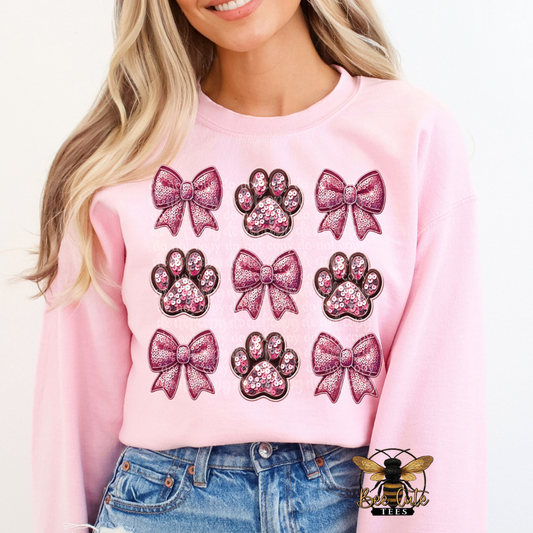 Person wearing a pink sweatshirt with glittery bow and paw print designs.