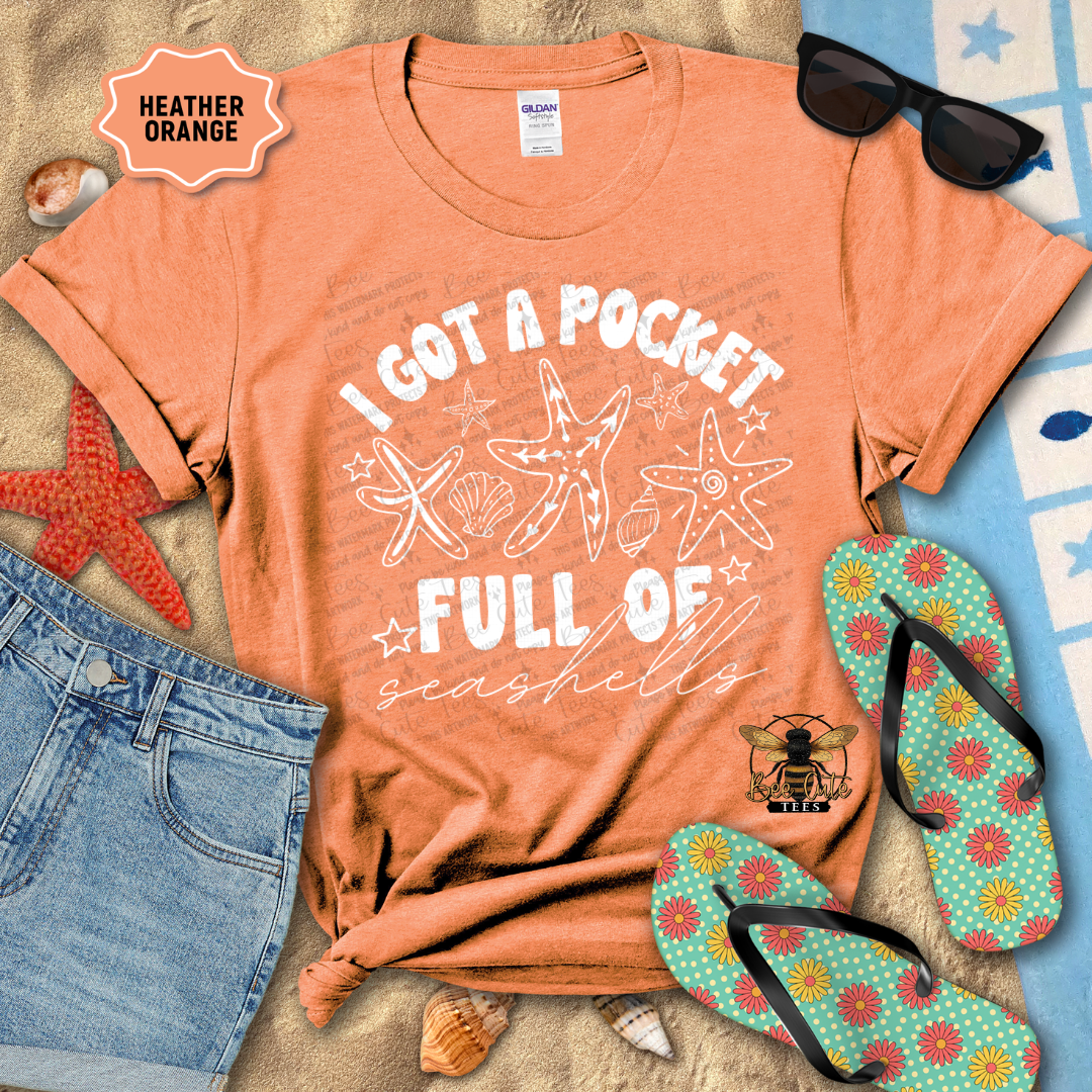 Orange t-shirt with starfish design and text, sunglasses, jeans, and flip-flops on a beach-themed background.