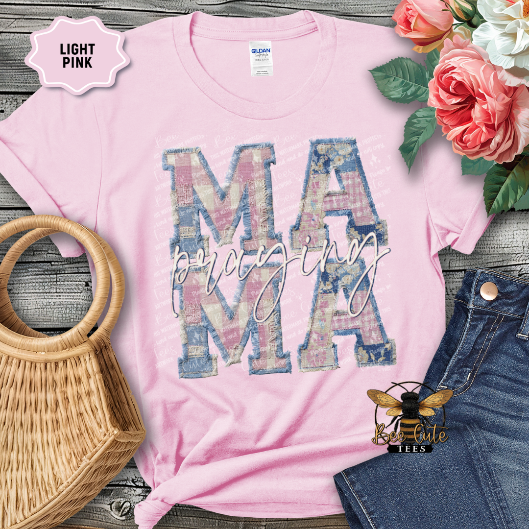 Light pink t-shirt with 'MAMA' design, surrounded by flowers and denim jeans on a wooden surface.