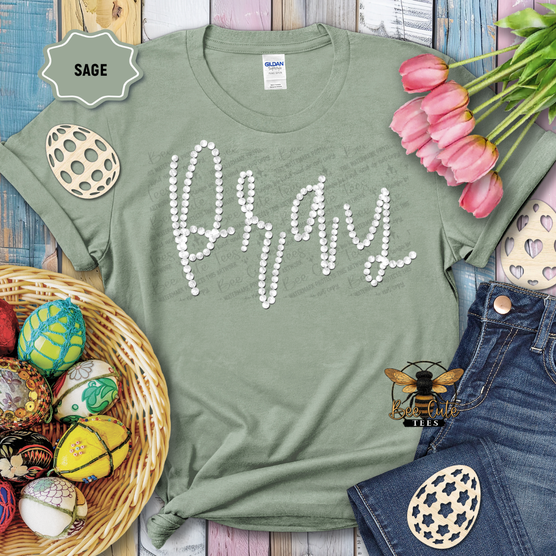 Green t-shirt with 'Pray' text, surrounded by Easter decorations on a wooden surface.