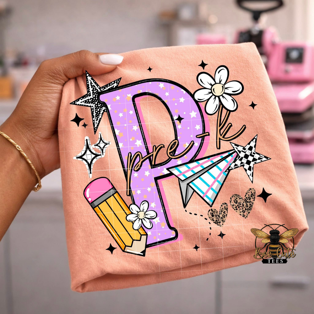 Folded orange t-shirt with decorative letter 'P' and illustrations, held by a hand.