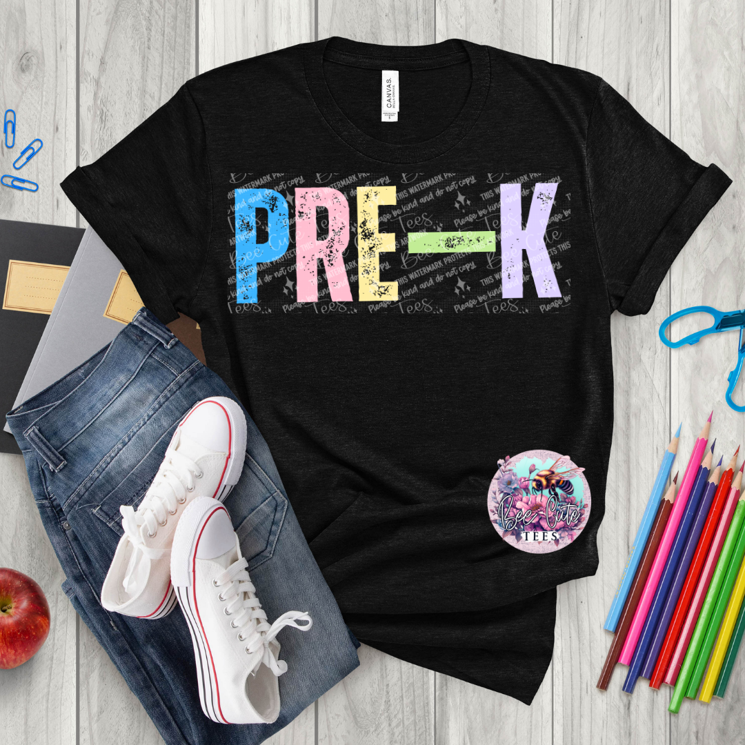 Black t-shirt with 'PRE-K' print on a wooden surface with school supplies.