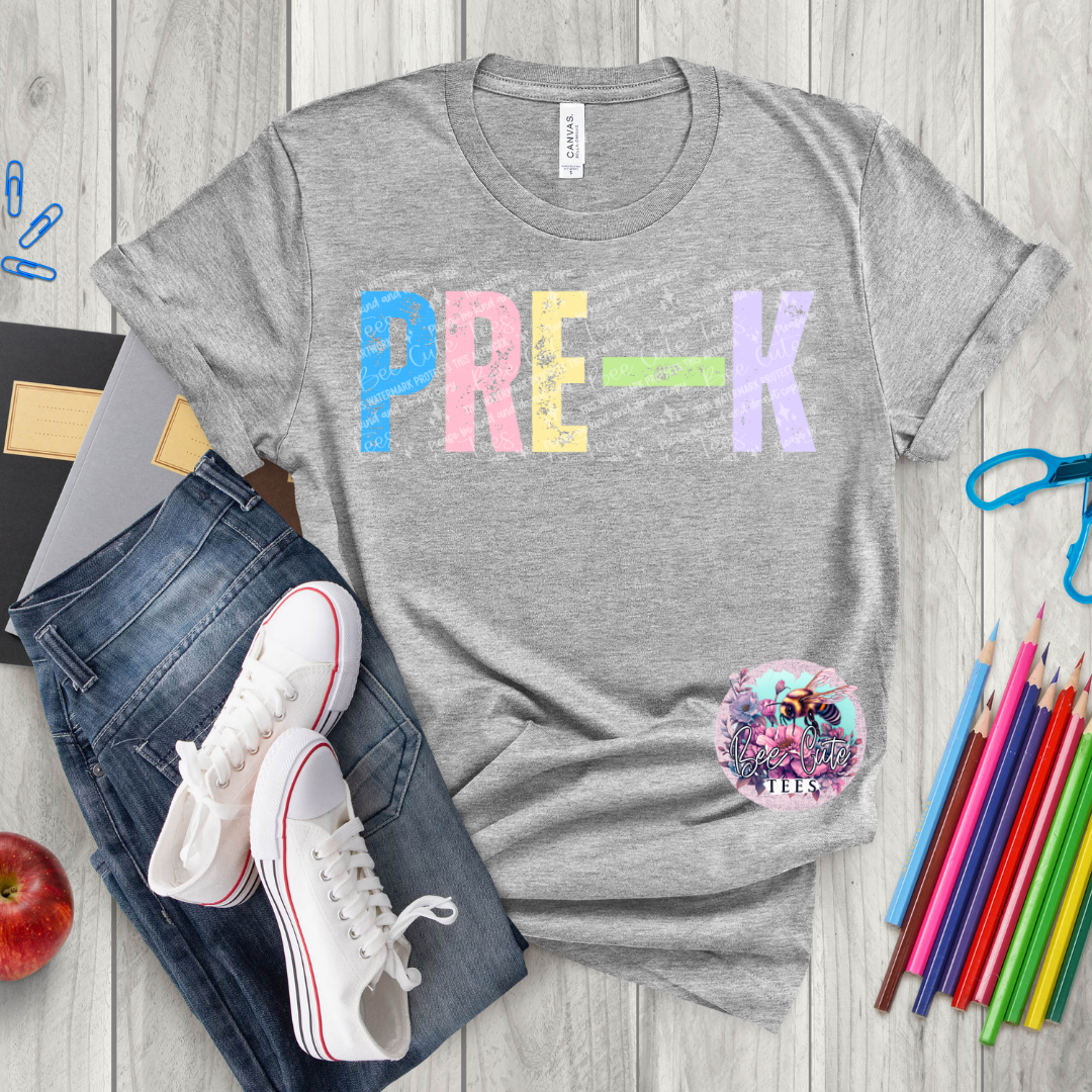 Gray t-shirt with 'PRE-K' print on a wooden surface with jeans, sneakers, and school supplies.