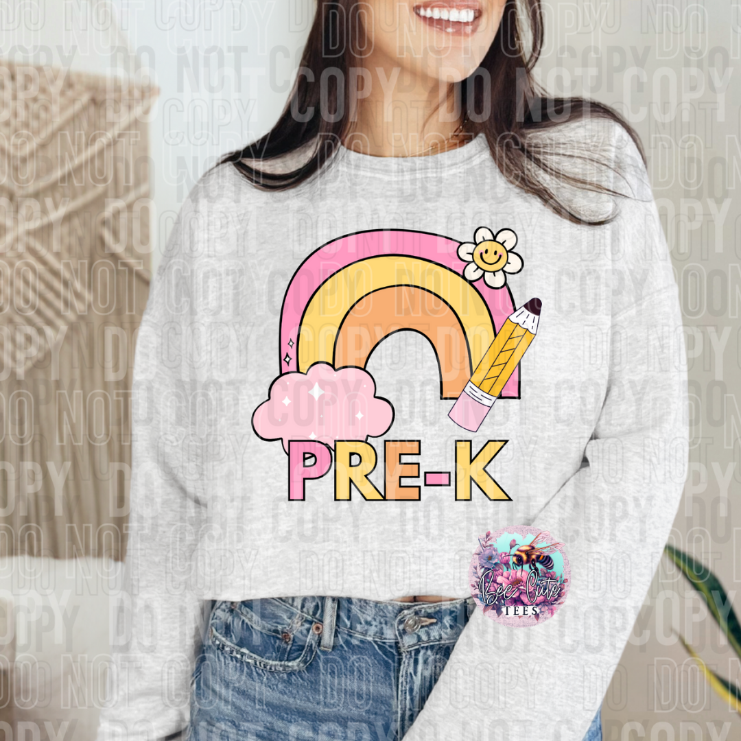 Person wearing a white sweatshirt with a colorful rainbow and pencil design, labeled 'PRE-K'.