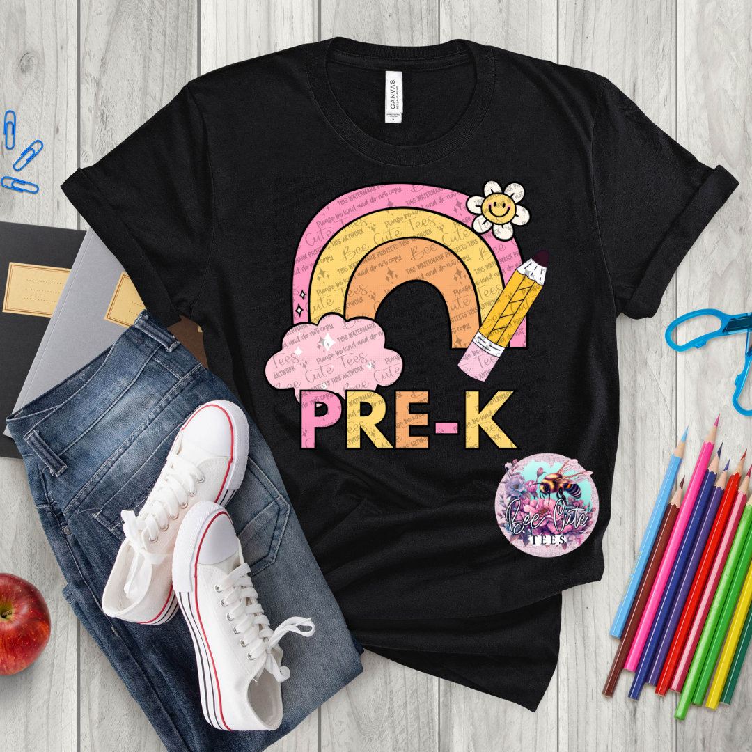 Black t-shirt with a rainbow and 'PRE-K' design on a wooden surface with school supplies.