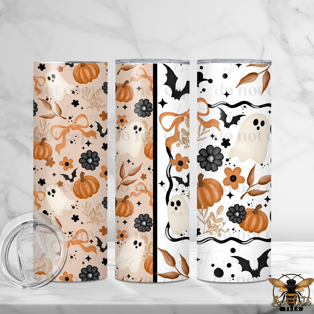 Three slim tumblers with Halloween-themed patterns are displayed on a white marble surface with a clear lid in the foreground. The designs feature pumpkins, ghosts, bats, flowers, and leaves in orange, black, and white.