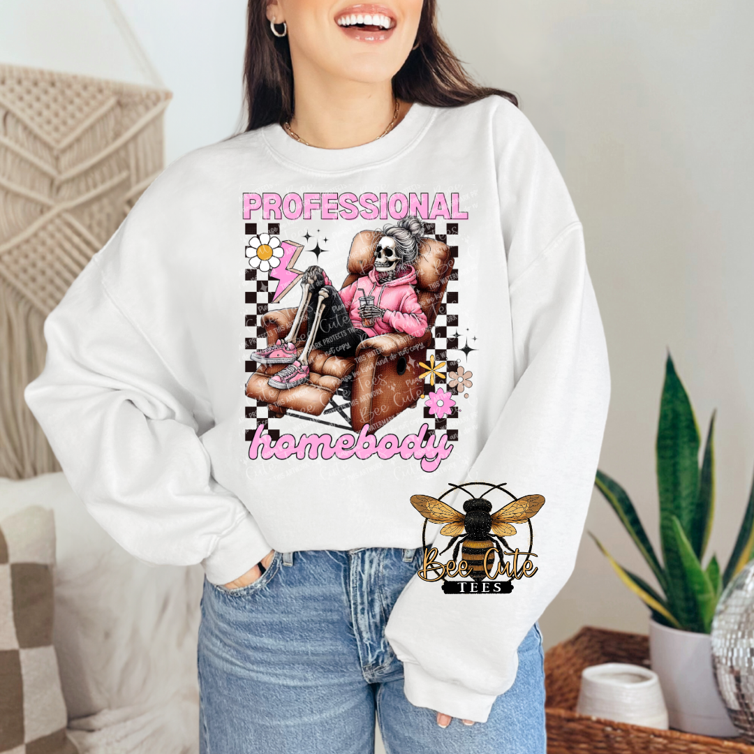 Person wearing a white sweatshirt with a graphic design and text, sitting in a casual indoor setting.
