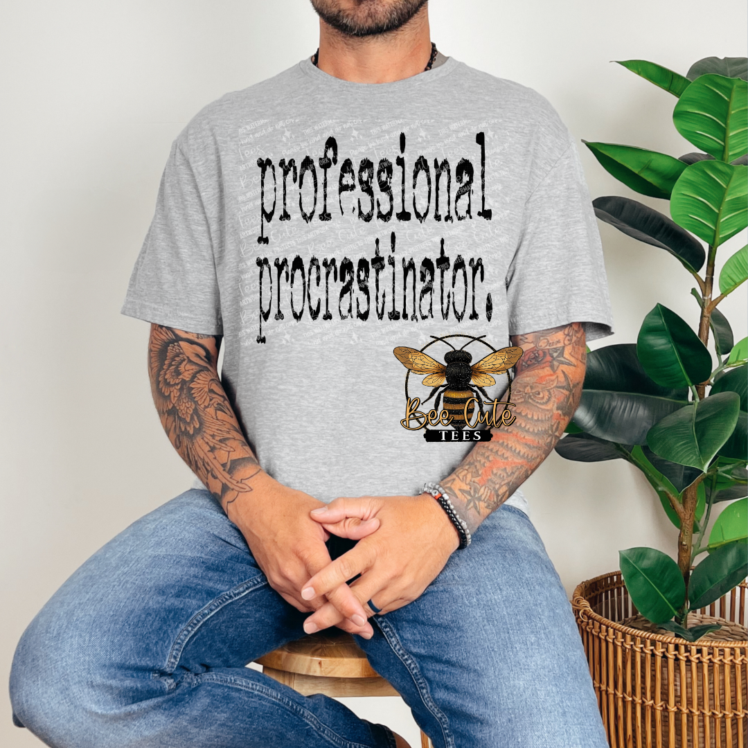 Person wearing a gray t-shirt with 'professional procrastinator' text and a bee logo, sitting next to a plant.