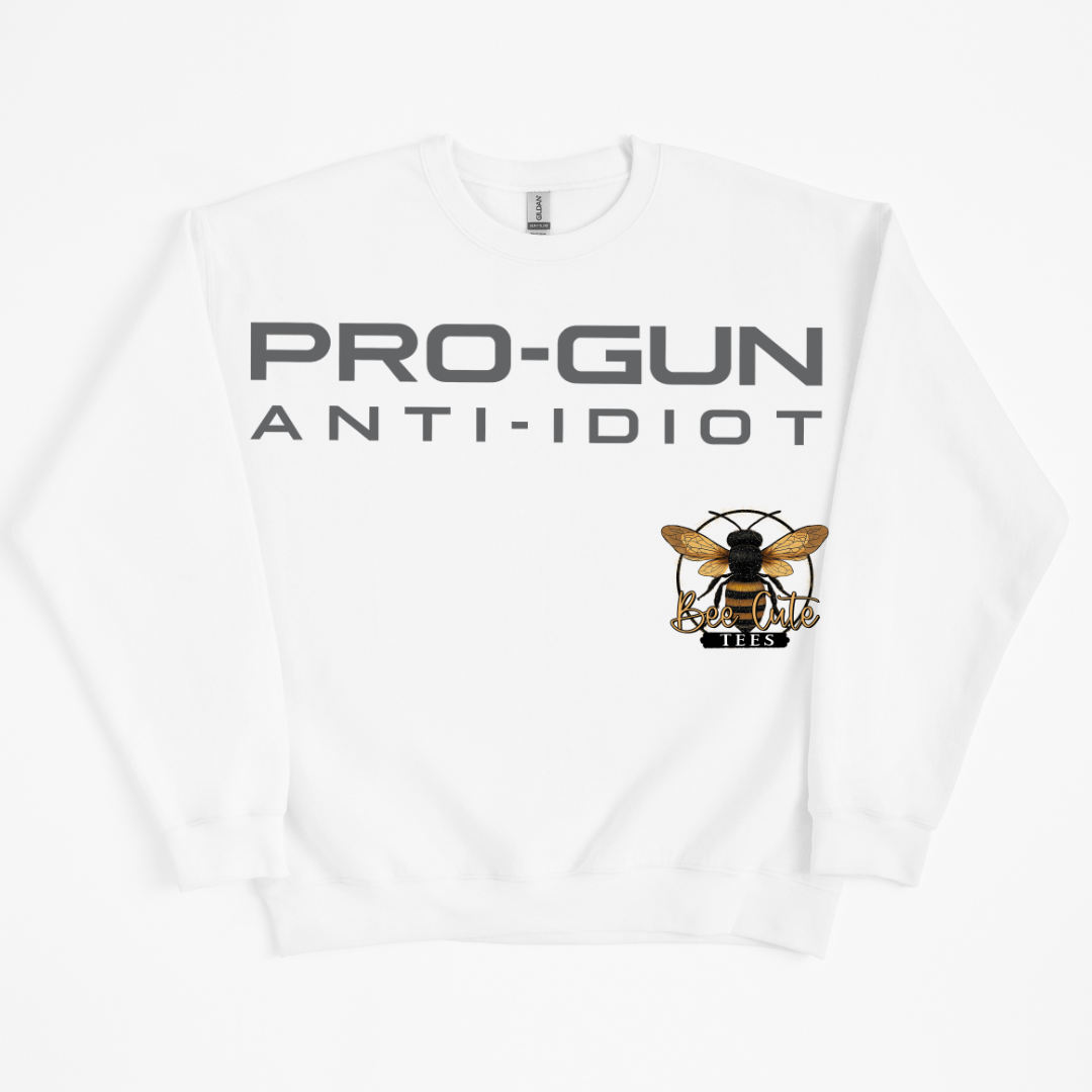 A white crewneck sweatshirt with 'PRO-GUN ANTI-IDIOT' printed in bold gray letters across the chest, accompanied by a graphic of a bee logo.
