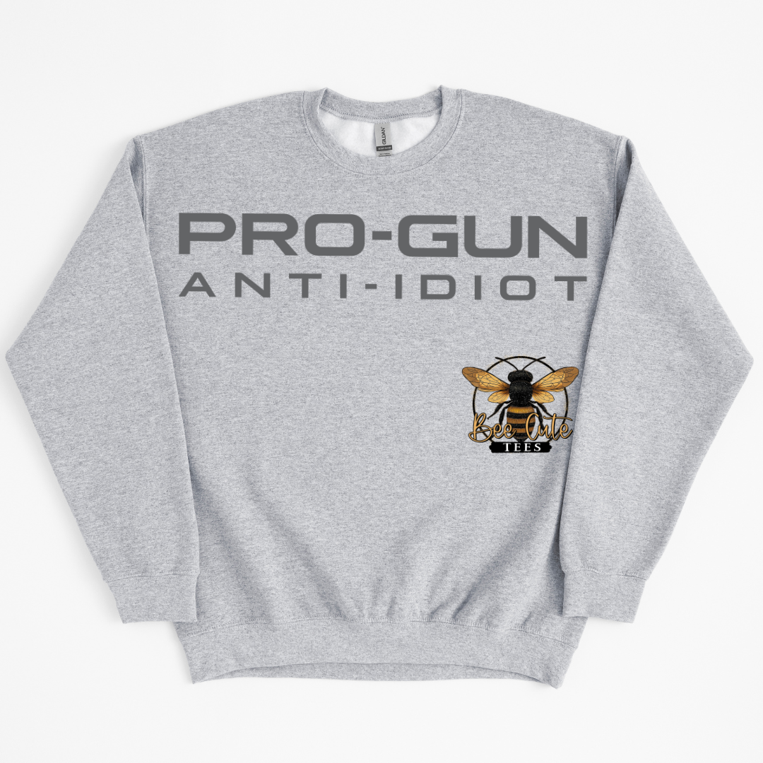 A heather gray crewneck sweatshirt featuring the text 'PRO-GUN ANTI-IDIOT' in dark gray across the chest, with a graphic of a bee a logo.