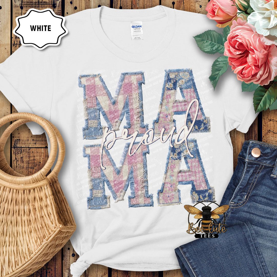 White t-shirt with 'Proud Mama' design on a wooden surface with flowers and denim jeans.