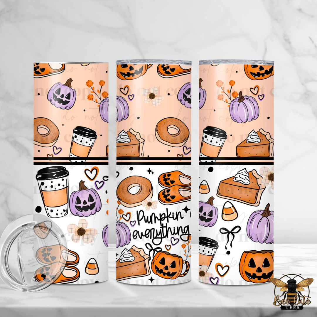 Three tall insulated tumblers with clear lids are shown on a light marble surface. The tumblers have a Halloween-themed pattern with pumpkins, jack-o'-lanterns, coffee cups, donuts, candy corn, and pie slices on peach and white backgrounds.