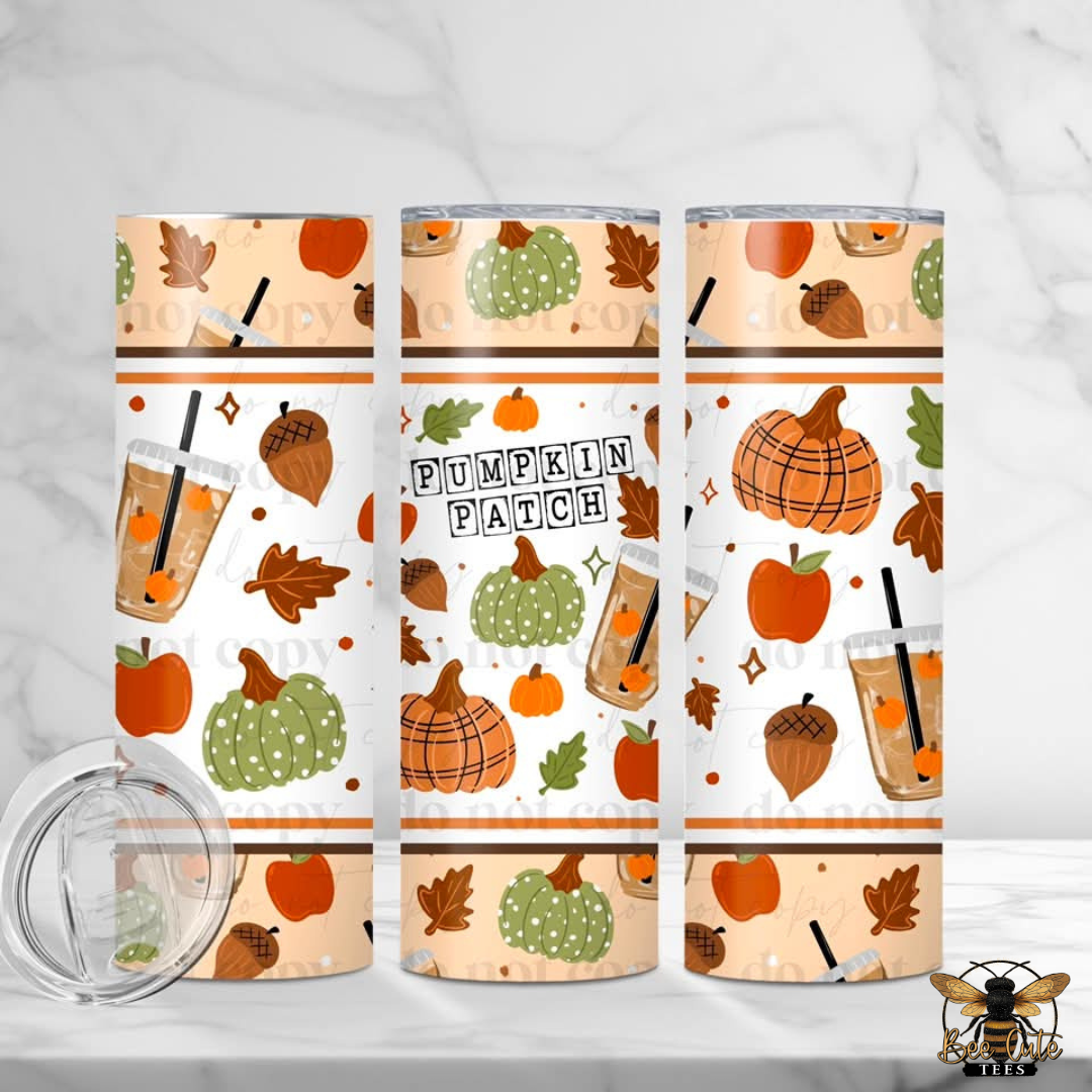 Three insulated tumblers with a fall 'Pumpkin Patch' pattern are displayed on a white marble surface with a clear lid in the foreground. The pattern features orange pumpkins, green striped pumpkins, acorns, leaves, and iced coffee illustrations on a cream background.