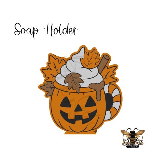 A Halloween-themed soap holder featuring a carved orange pumpkin mug filled with whipped cream, autumn leaves, and a cinnamon stick, shown on a white background with the text 'Soap Holder' and a small bee logo in the bottom right.