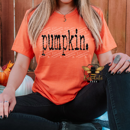 Person wearing an orange t-shirt with 'pumpkin' text, sitting against a wooden fence.