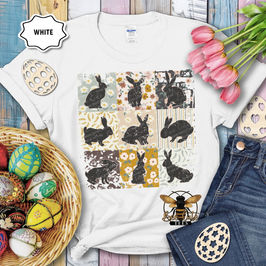 White t-shirt with rabbit pattern, surrounded by Easter decorations on a wooden surface.