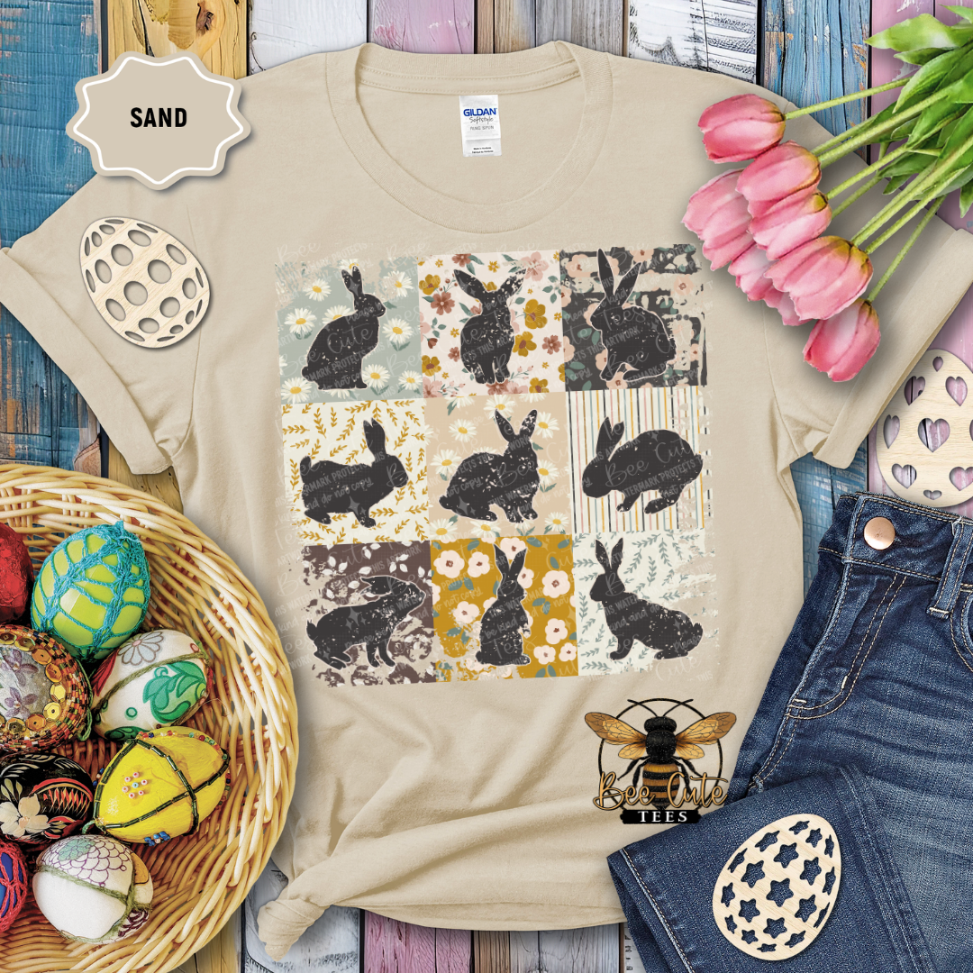 Beige t-shirt with rabbit pattern, surrounded by Easter decorations on a wooden surface.