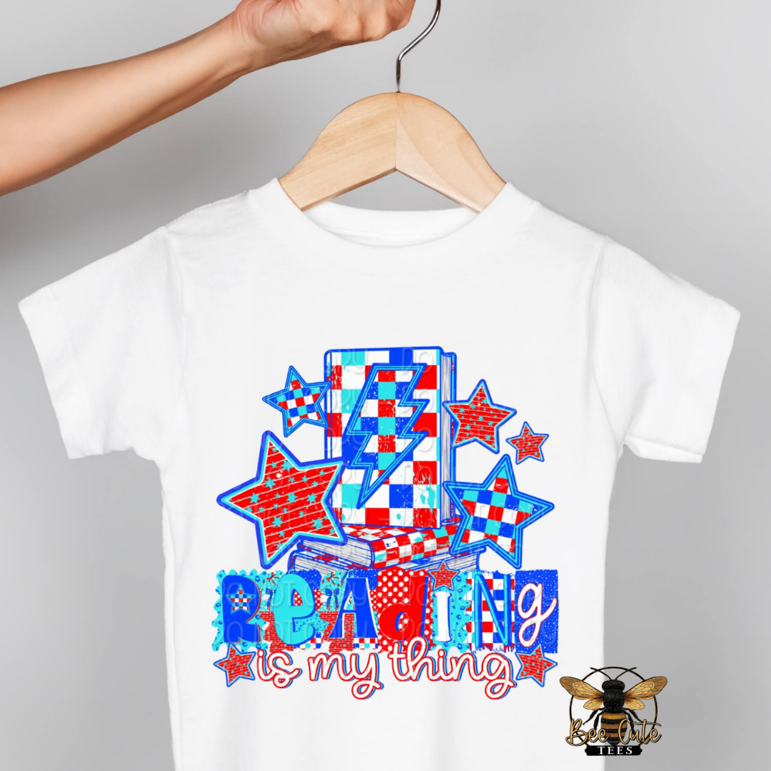 White t-shirt with colorful design and 'Reading is my thing' text on a gray background