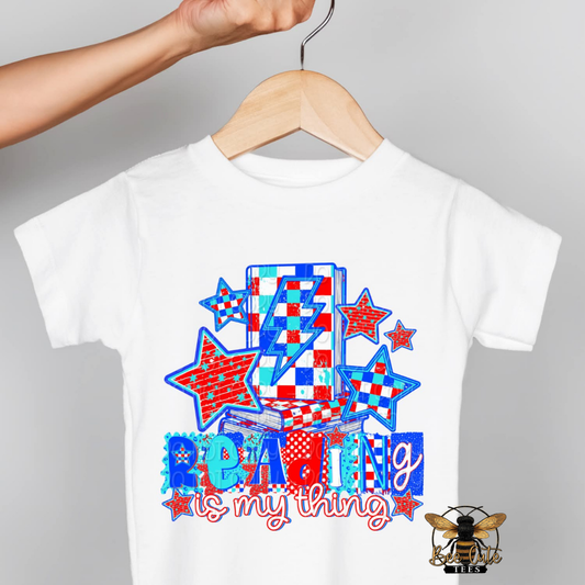 White t-shirt with colorful design and 'Reading is my thing' text on a gray background
