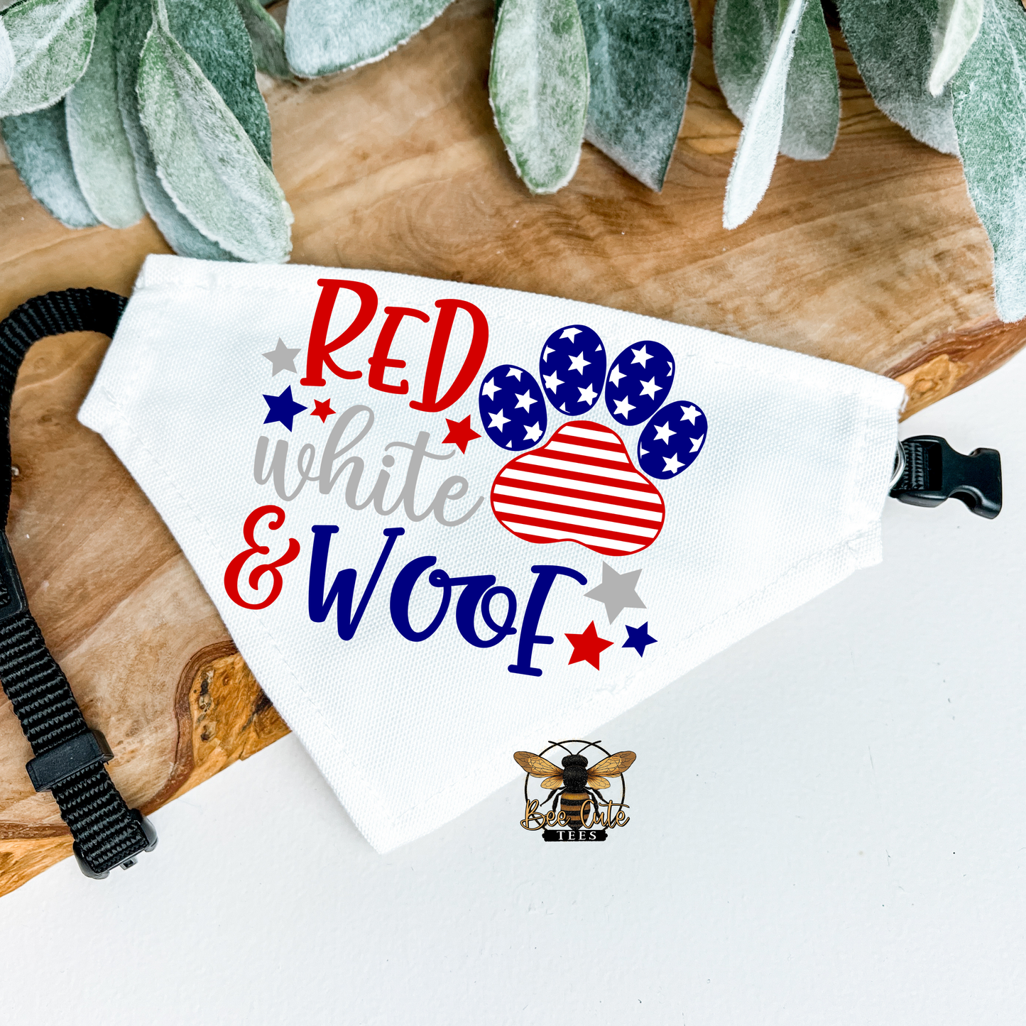 Dog bandana with 'Red white & woof' text and paw print design on a wooden surface.