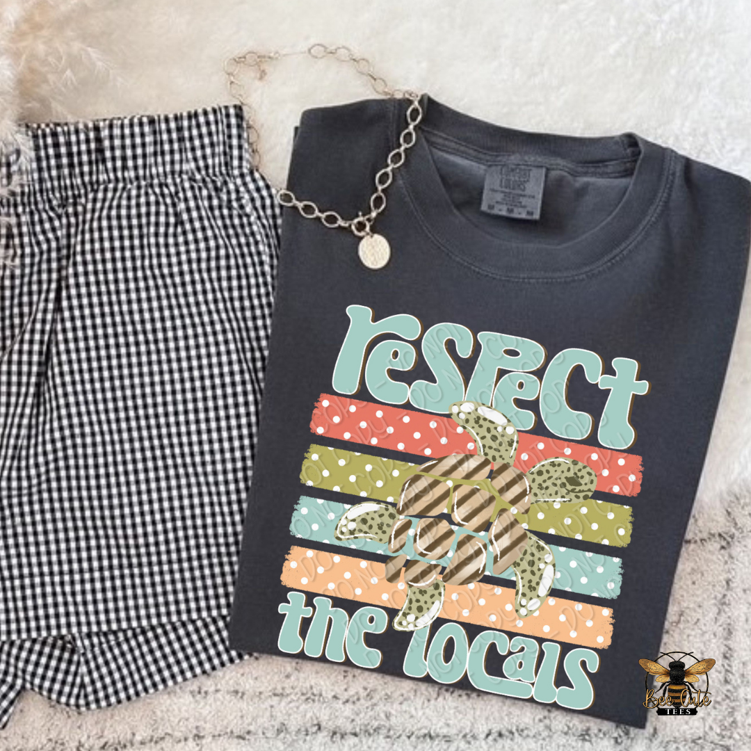 Black t-shirt with 'Respect the Locals' graphic and checkered pants on a textured surface
