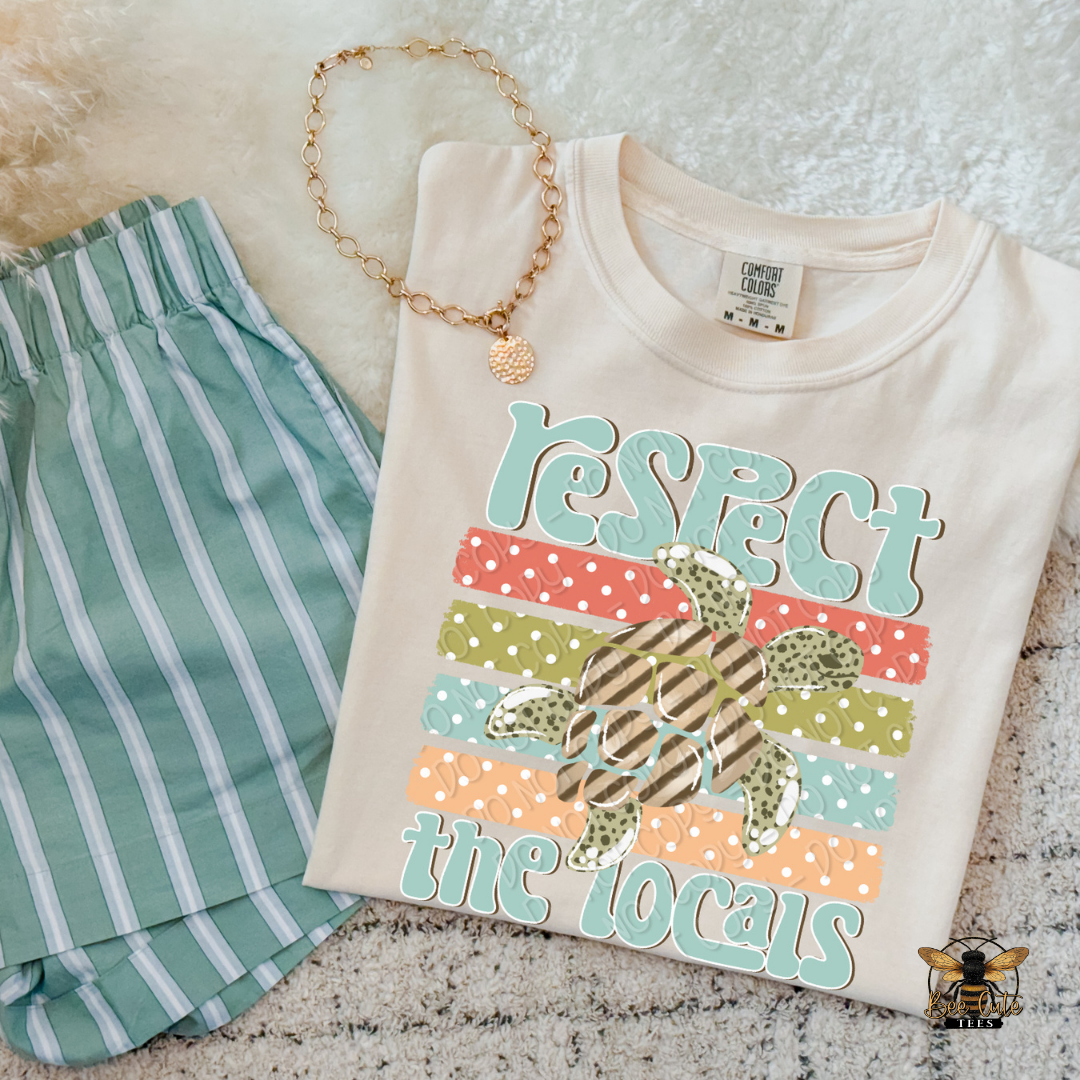 Beige t-shirt with 'Respect the Locals' text and green shorts on a textured surface