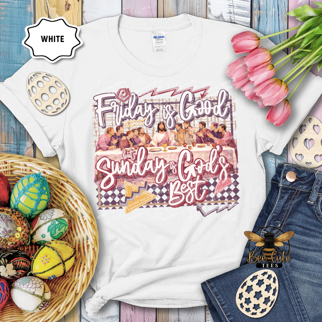 White t-shirt with 'Friday is Good, Sunday is God's Best' graphic design on a wooden surface with Easter decorations.