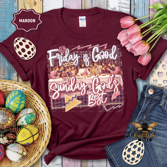 Maroon t-shirt with 'Friday is Good, Sunday is God's Best' graphic design on a wooden surface with Easter decorations.