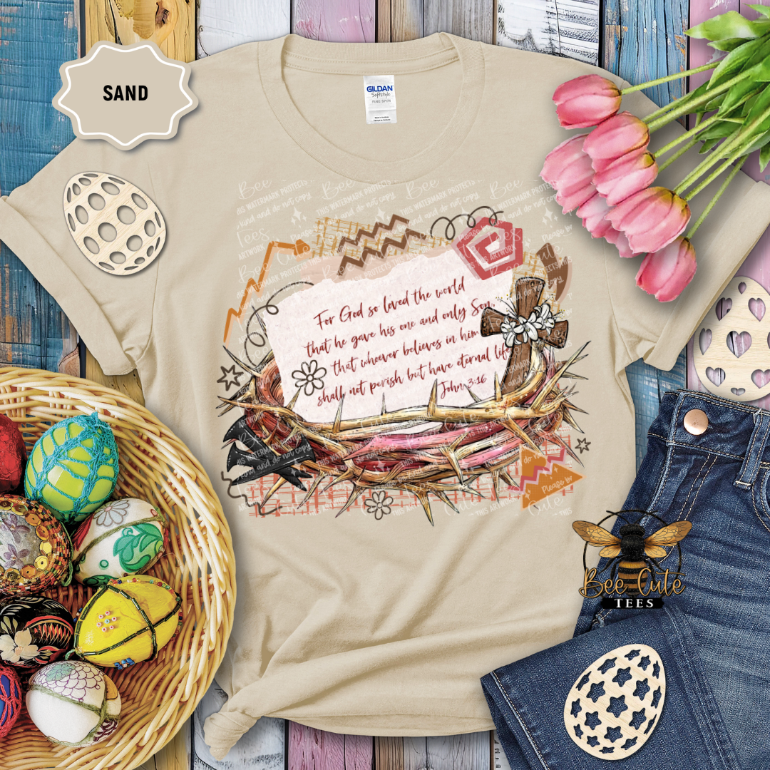 Beige t-shirt with a colorful design featuring text and nature elements, surrounded by Easter decorations and flowers.