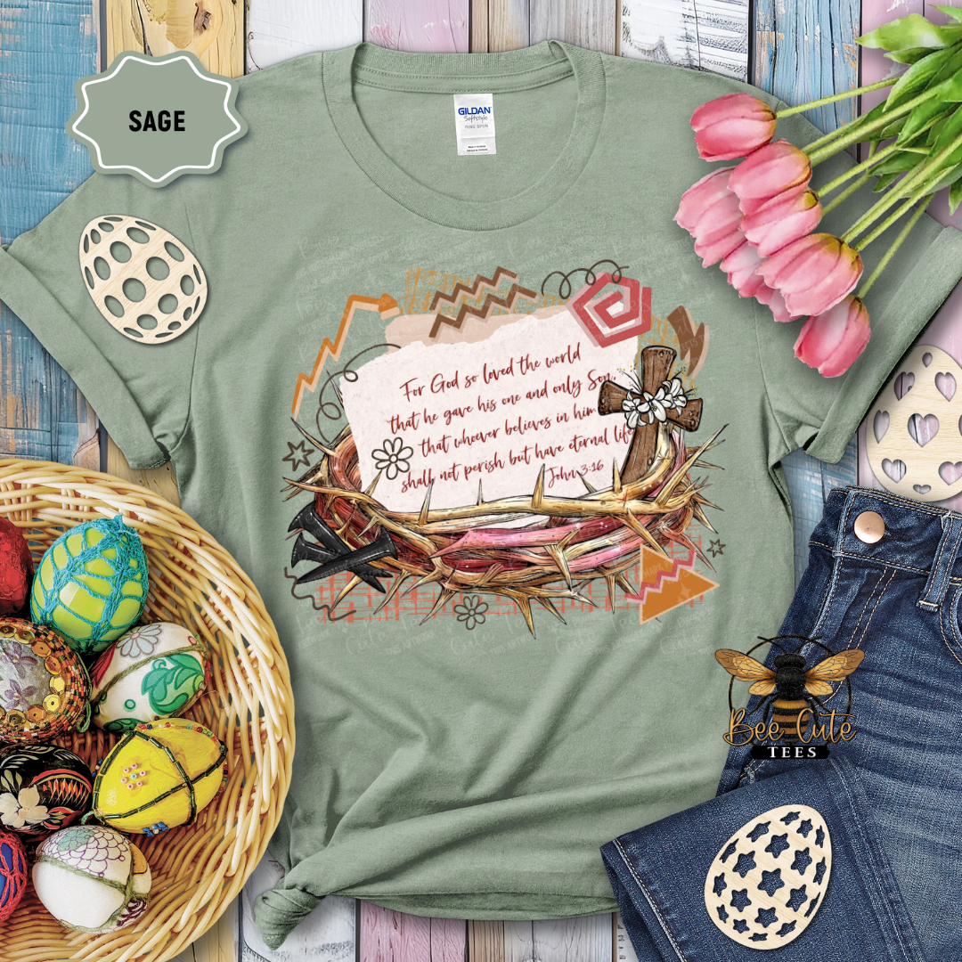 Green t-shirt with a cross and nature design, surrounded by Easter decorations on a wooden surface.