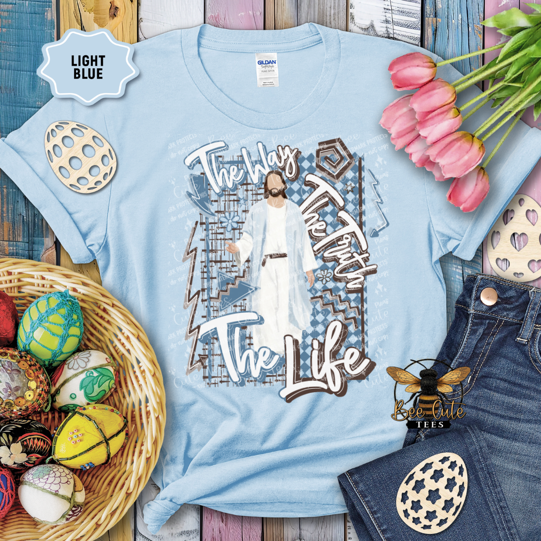 Light blue t-shirt with graphic design and text, surrounded by Easter decorations and jeans.
