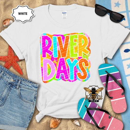White t-shirt with 'River Days' design, sunglasses, and flip-flops on a beach-themed background.