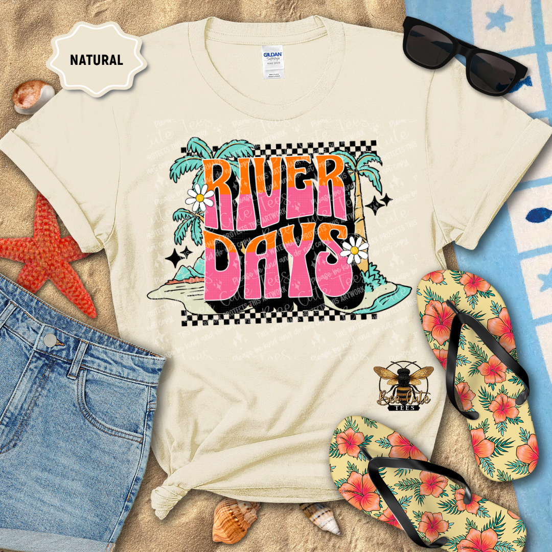 Beige t-shirt with 'River Days' graphic design, sunglasses, flip-flops, and beach accessories on a natural background.