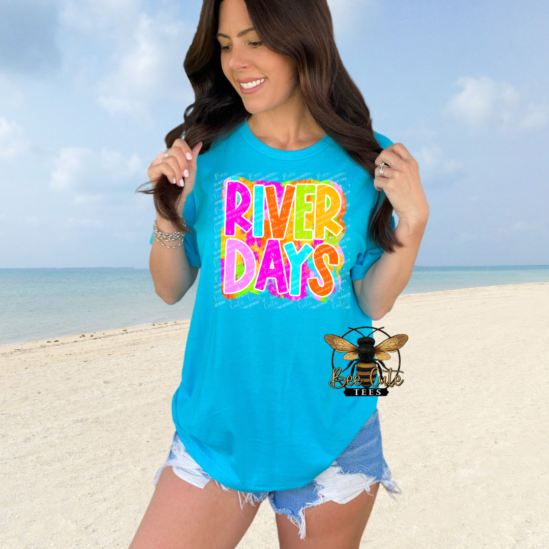 Woman wearing a blue t-shirt with 'River Days' text on a beach