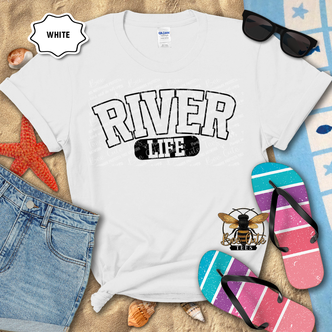 White t-shirt with 'River Life' design on a beach-themed background with sunglasses, flip-flops, and denim shorts.