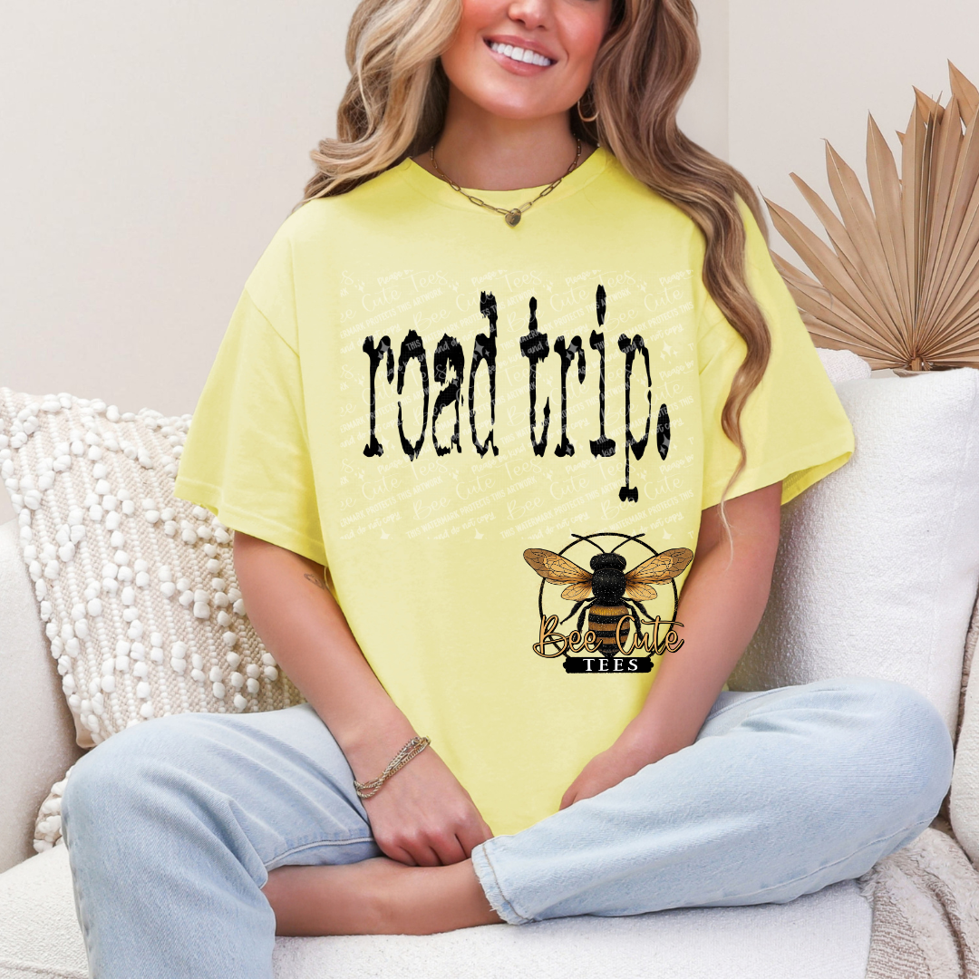 Person wearing a yellow 'road trip' t-shirt with a bee logo on a couch.