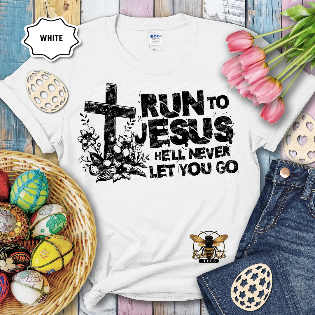 White t-shirt with 'Run to Jesus, hell never let you go' design on a wooden surface with Easter decorations.