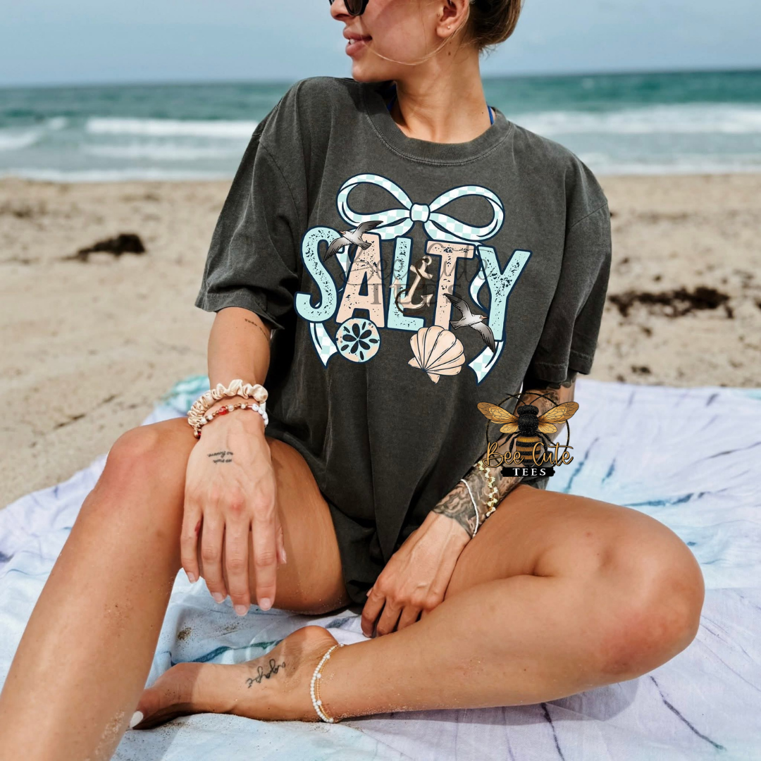 Person wearing a 'Salty' t-shirt on a beach