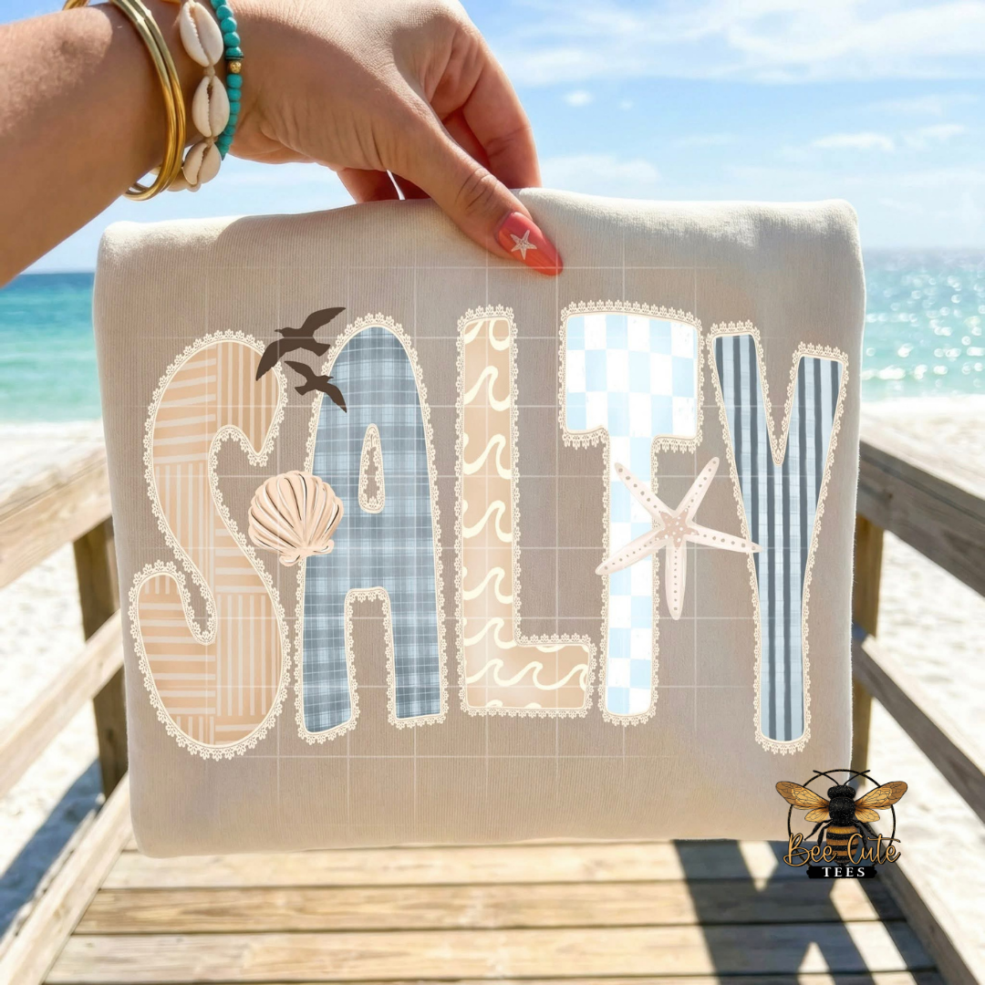 Beach-themed beige t-shirt with 'SALTY' text and ocean views