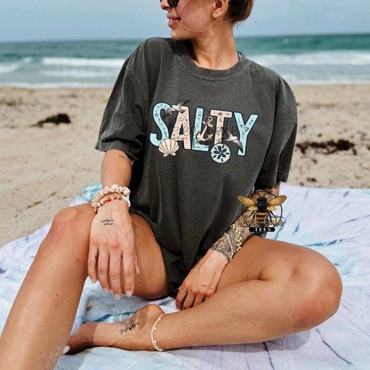 Person wearing a 'Salty' t-shirt on a beach