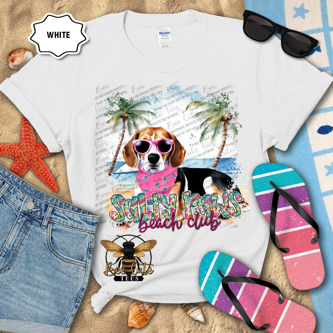 White t-shirt with a dog graphic and 'Beach Club' text on a sandy background with flip-flops and sunglasses.