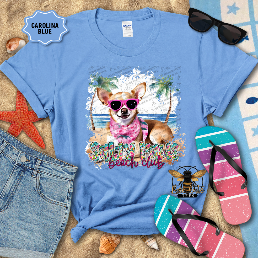 Blue t-shirt with a dog graphic and 'Beach Club' text, surrounded by beach accessories.