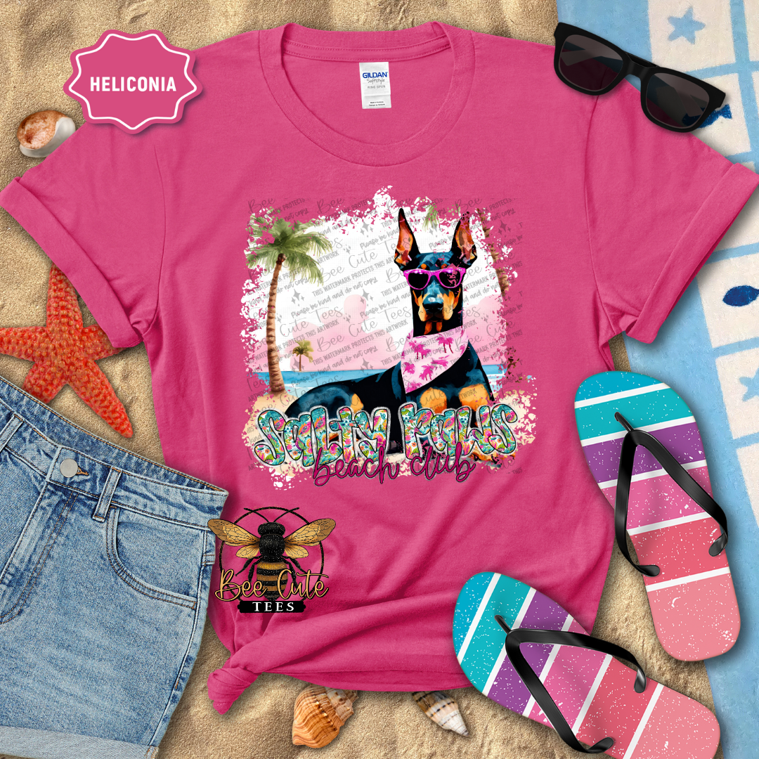 Pink t-shirt with a dog graphic and 'Beach Club' text, surrounded by beach accessories.