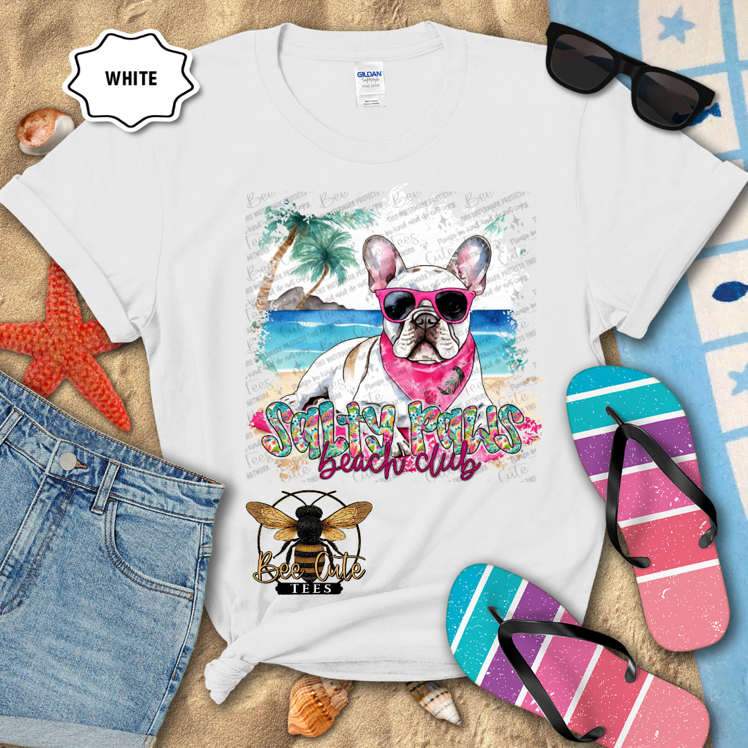 White t-shirt with a dog graphic and 'Beach Club' text, surrounded by beach accessories.