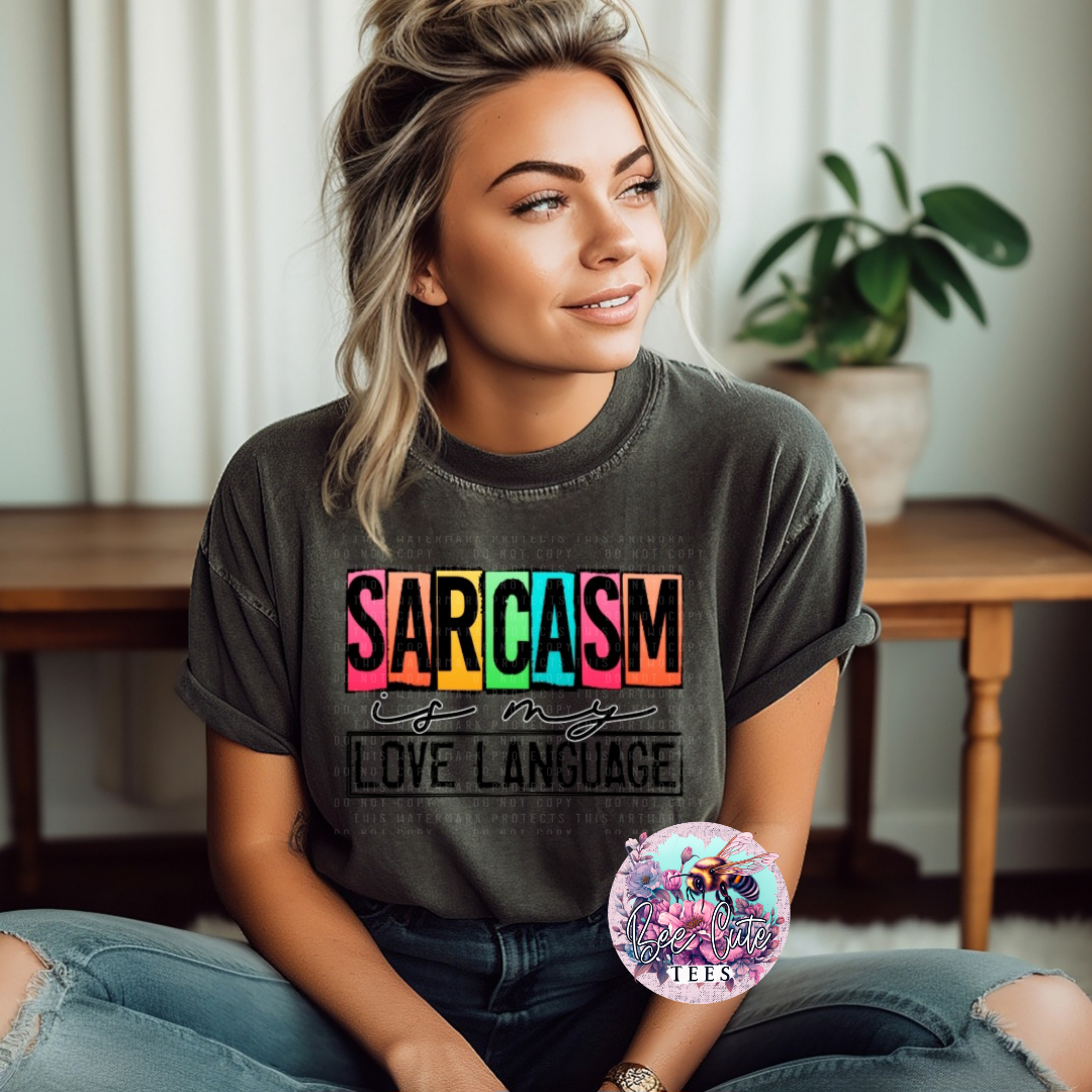 Woman wearing a t-shirt with 'SARCASM is my love language' text, sitting indoors.
