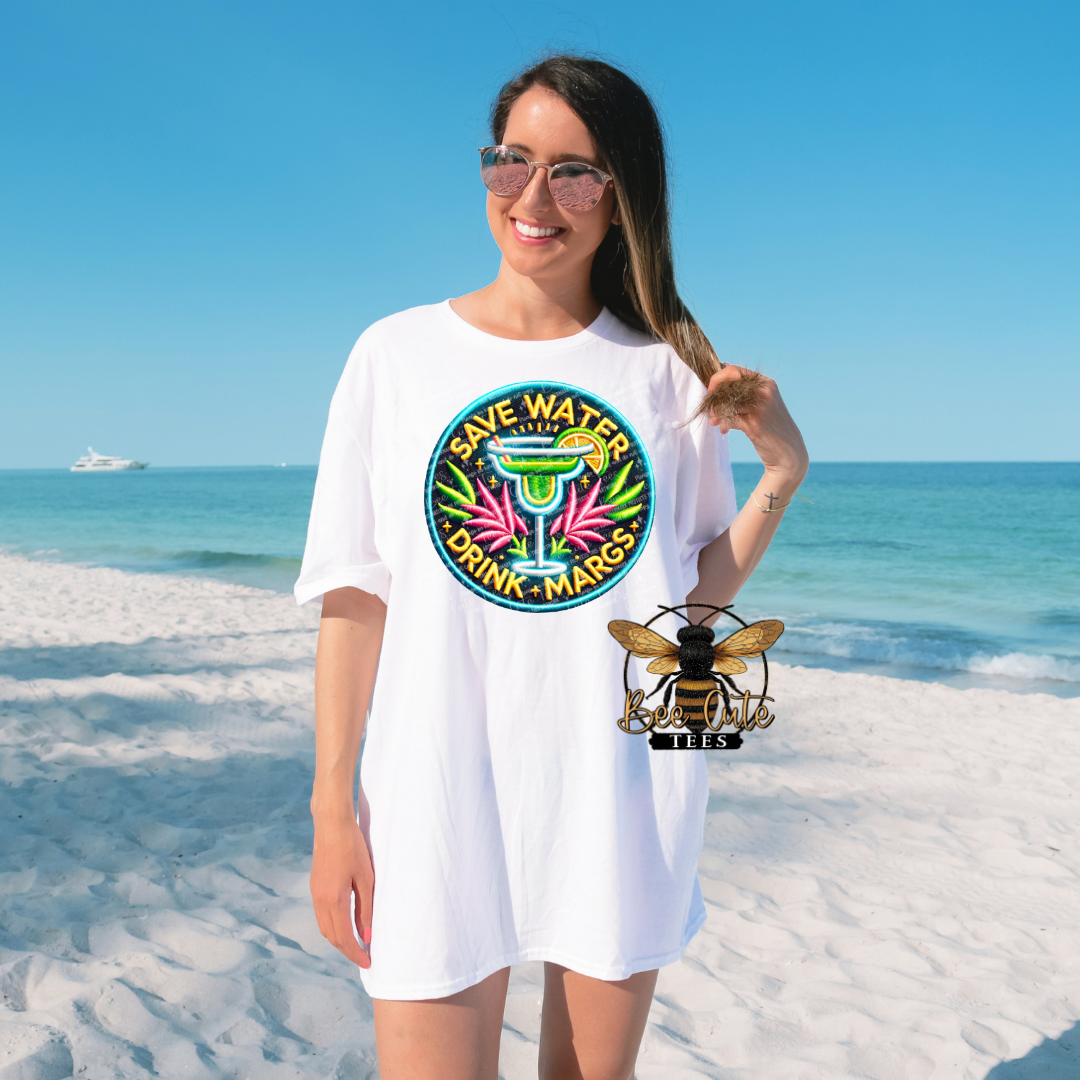 Woman wearing a white t-shirt with a colorful graphic design on a beach.