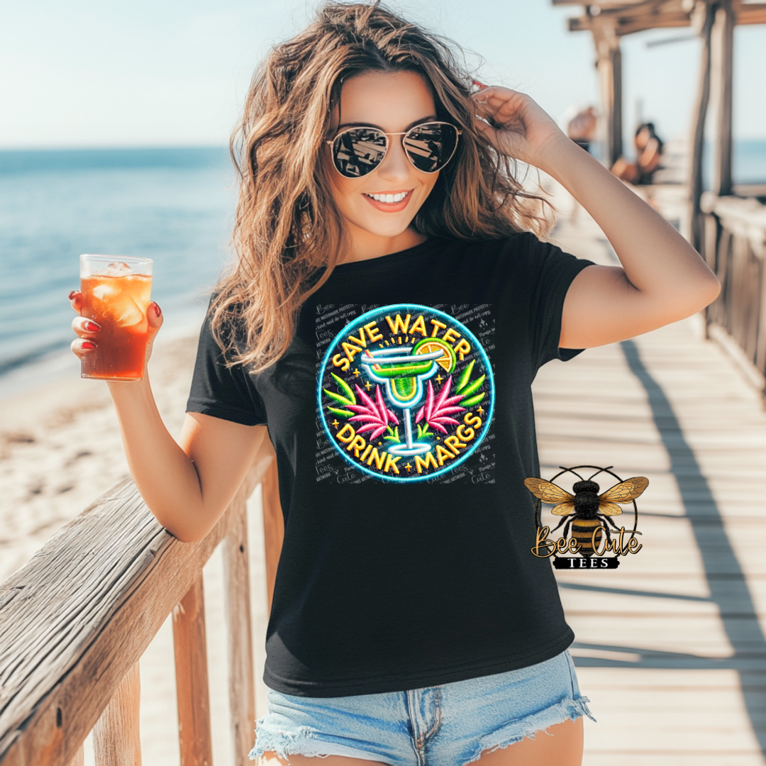 Woman on a beach holding a drink, wearing a 'Save Water Drink Margaritas' t-shirt.