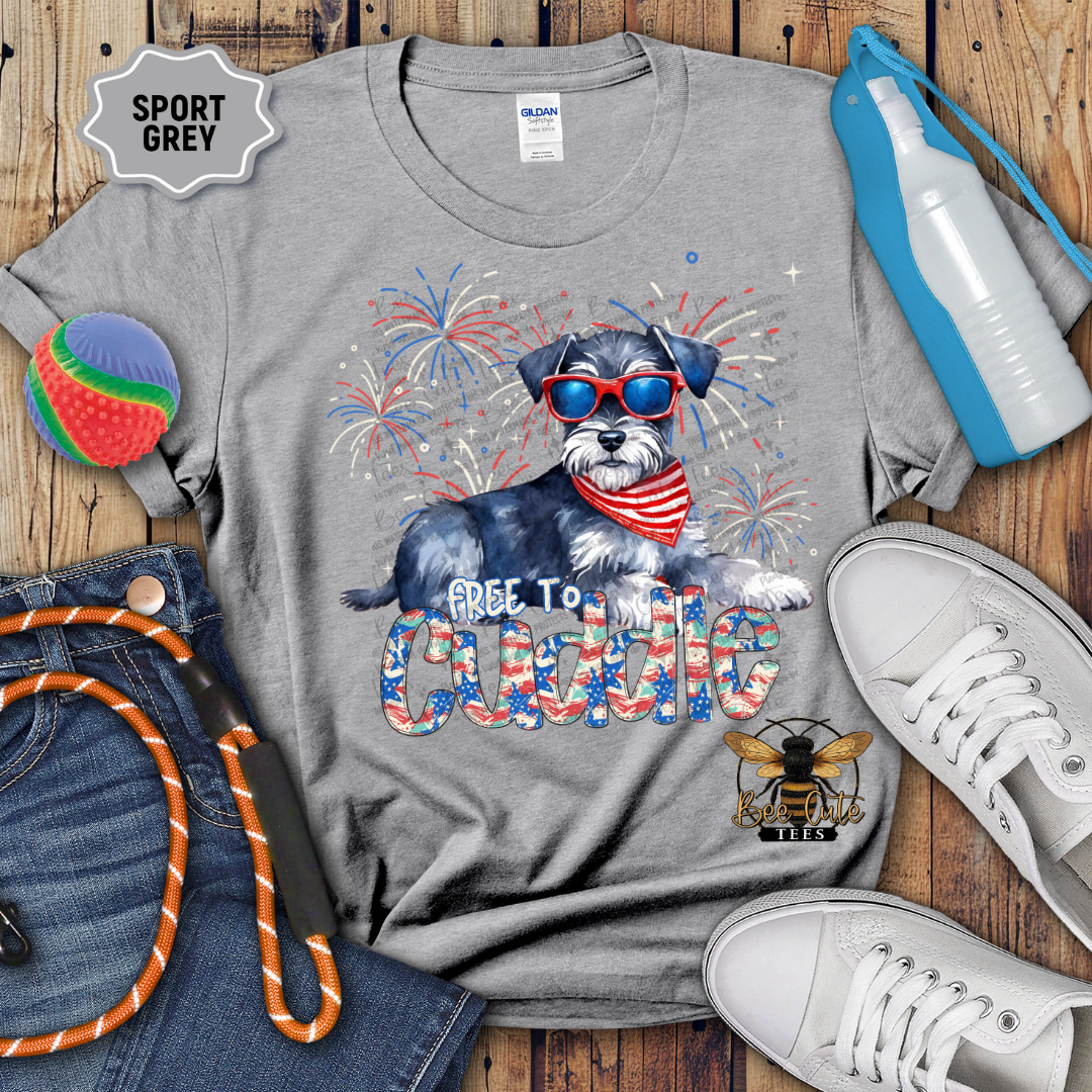 Gray t-shirt with a dog graphic and text on a wooden surface with accessories.