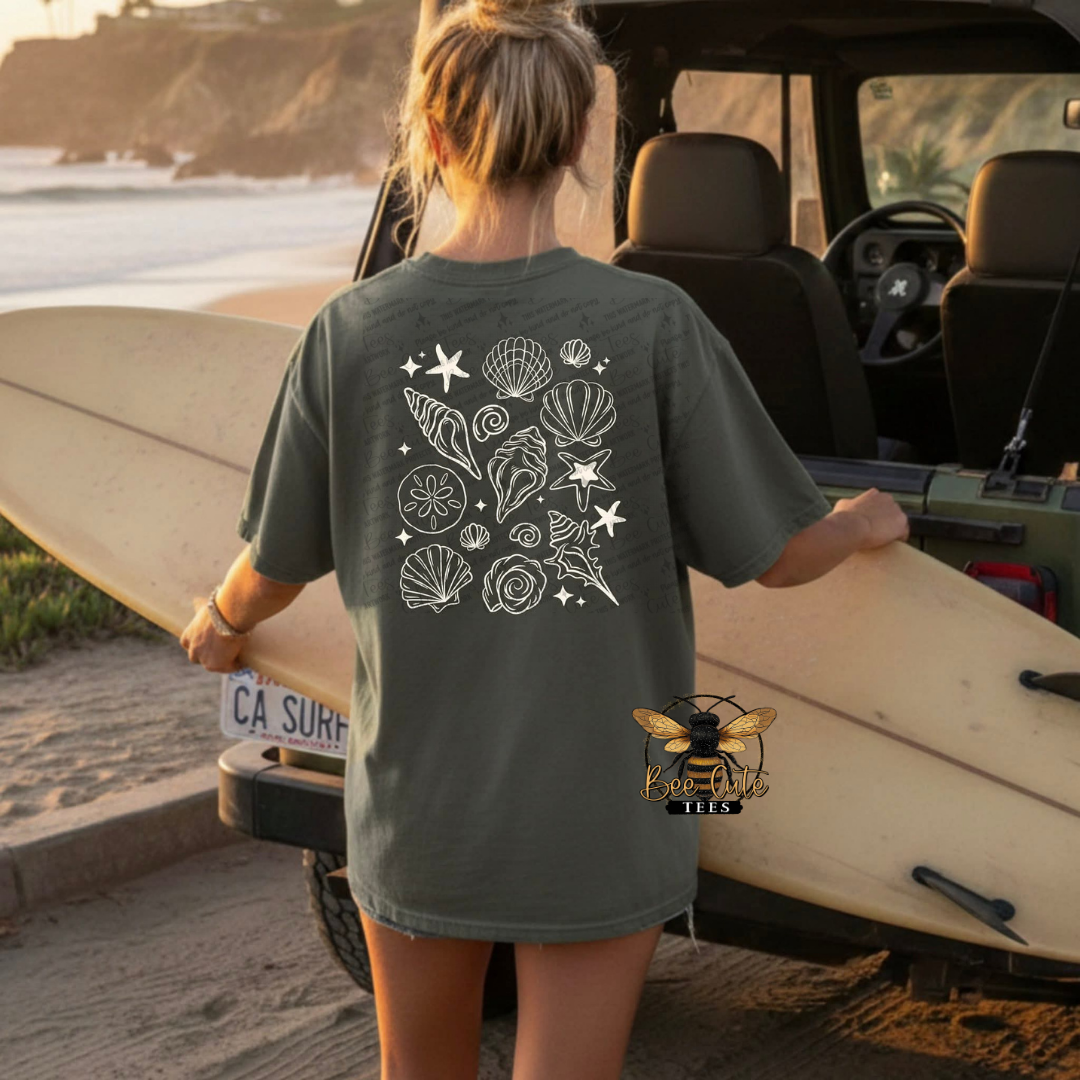 Person wearing a t-shirt with a shell design on the beach