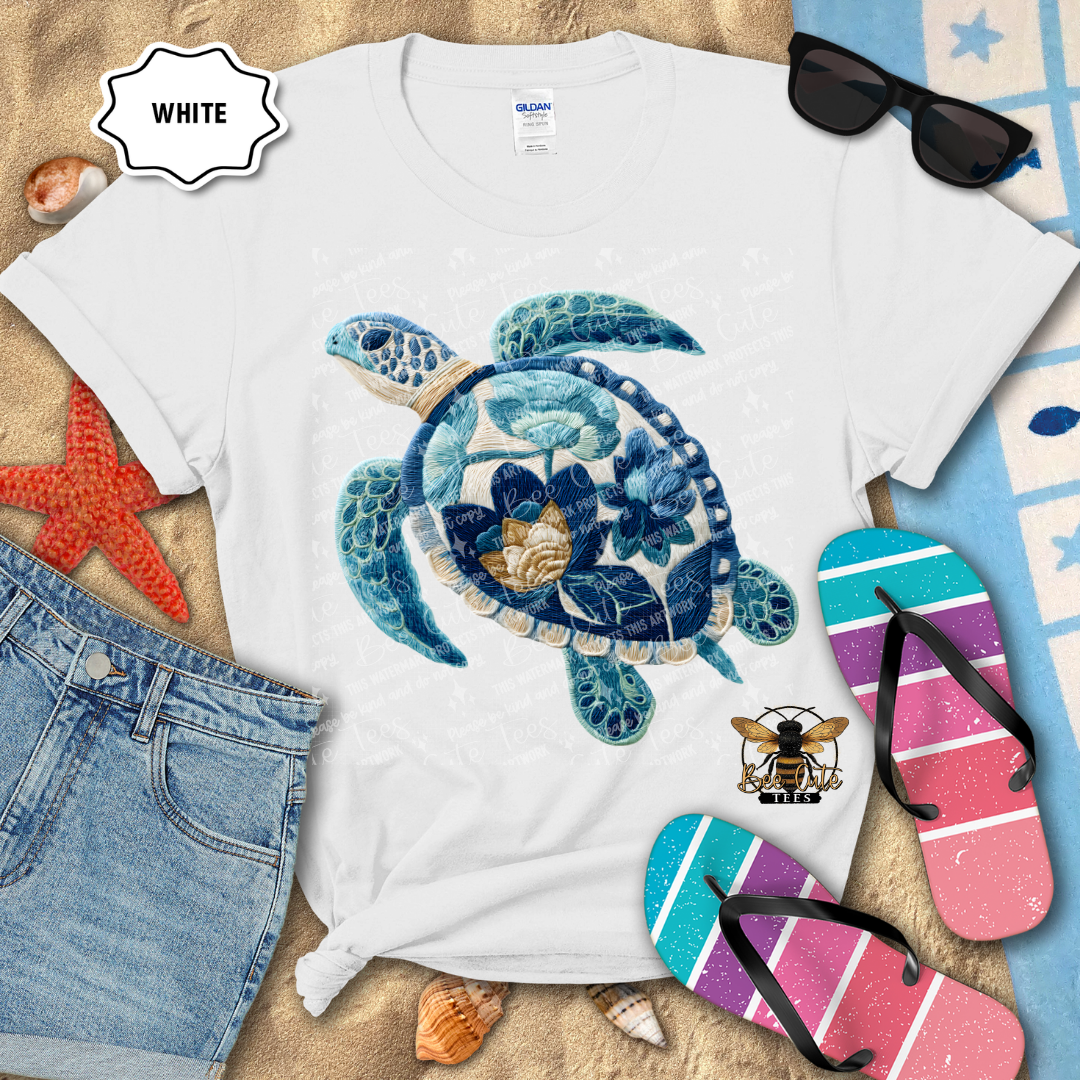 White t-shirt with a blue turtle design, sunglasses, and flip-flops on a beach-themed background.